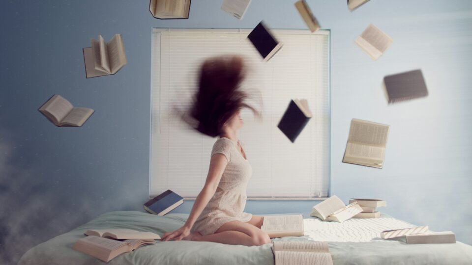 Dødsensangst for eksamener woman sitting on bed with flying books